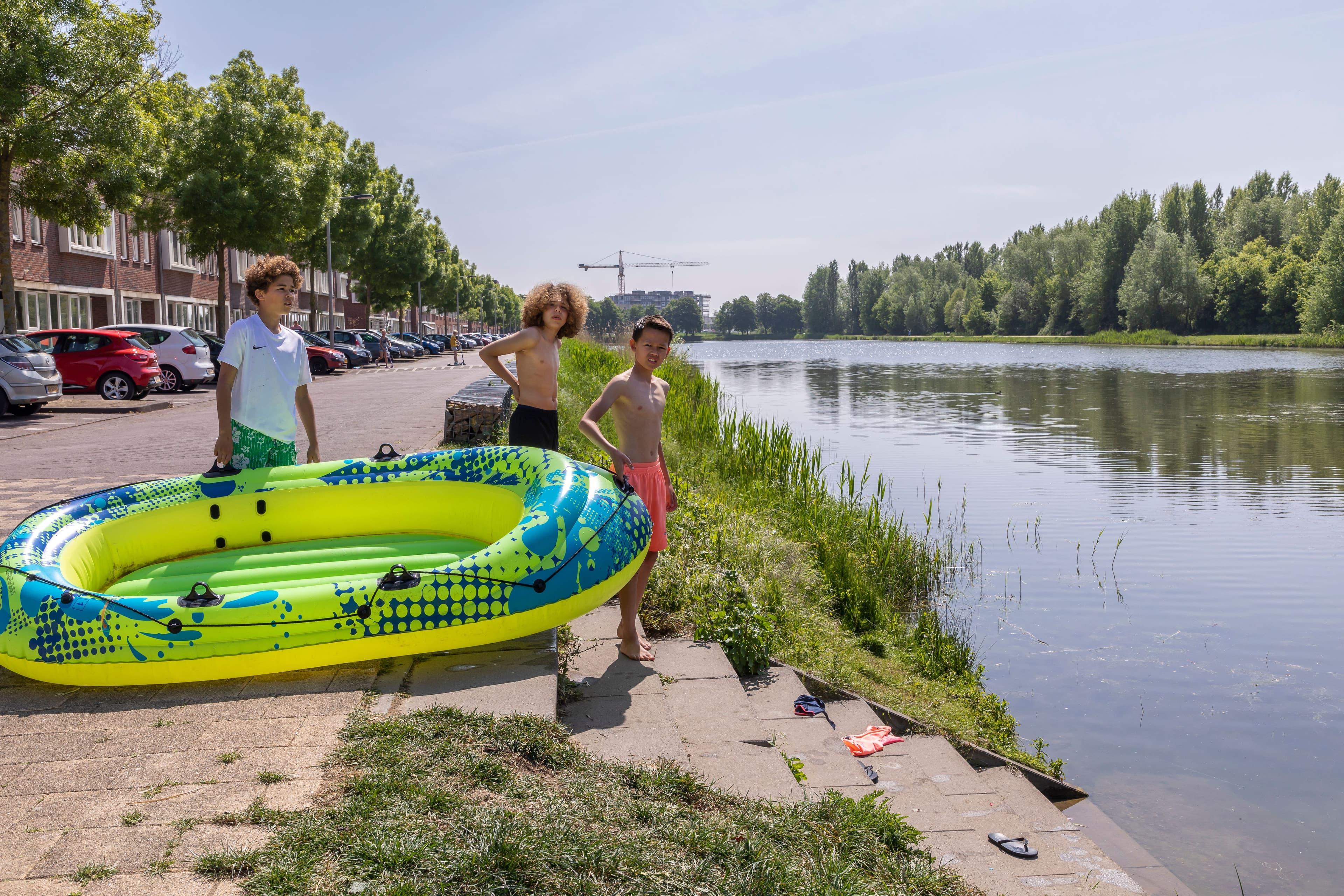 3 kinderen staan met een opblaasboot aan de waterkant