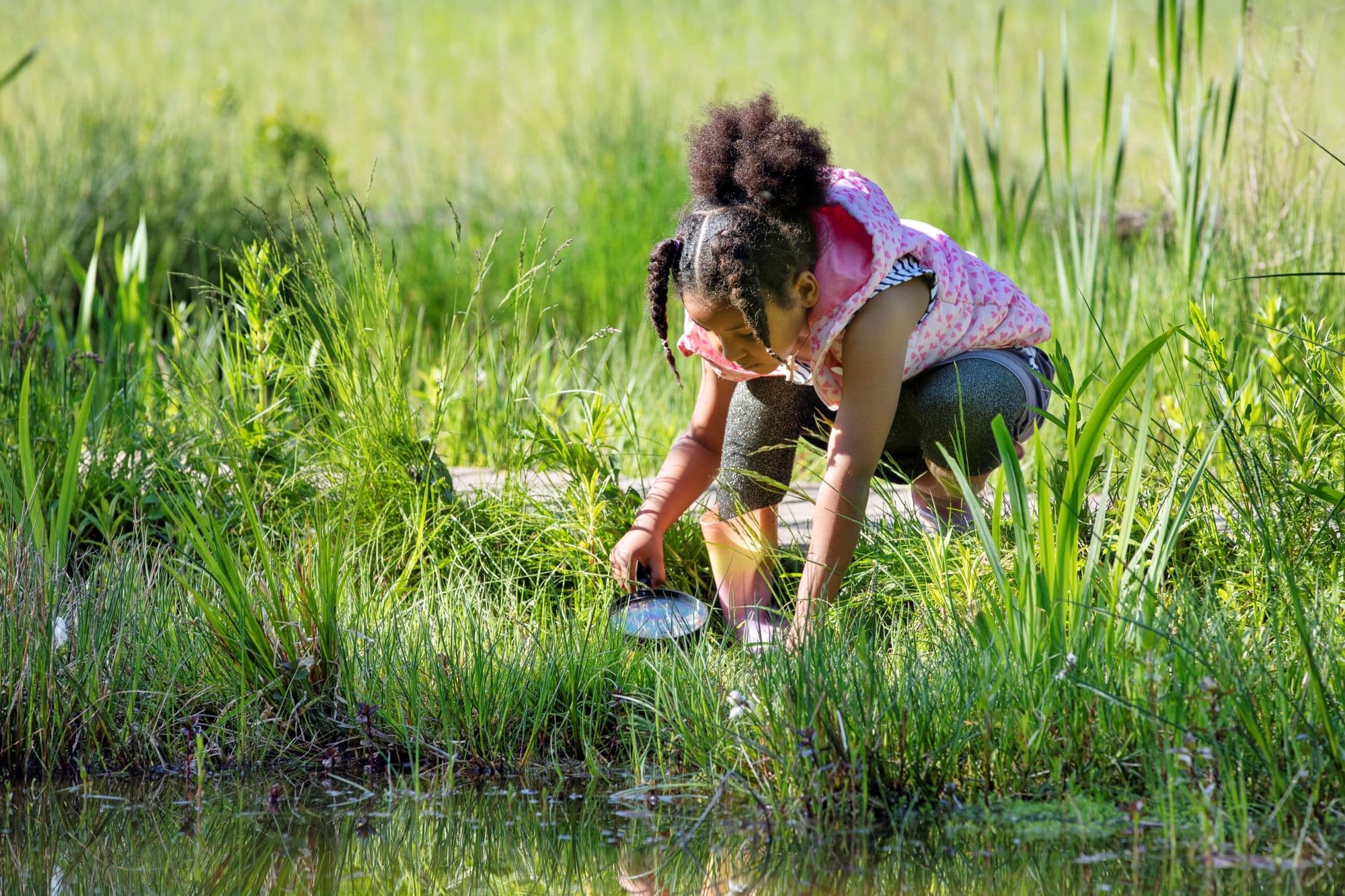 meisje kijkt met vergrootglas in natuurwater