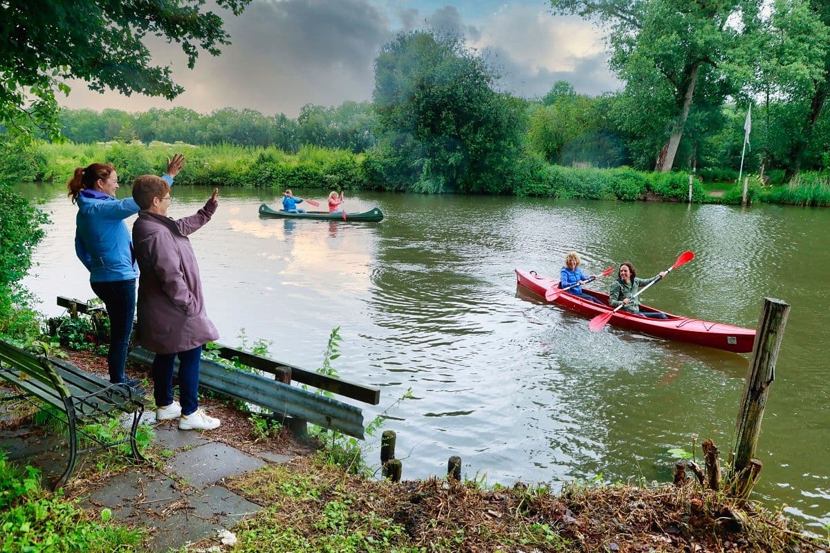 Mensen aan rivierkant kijken naar man in kano