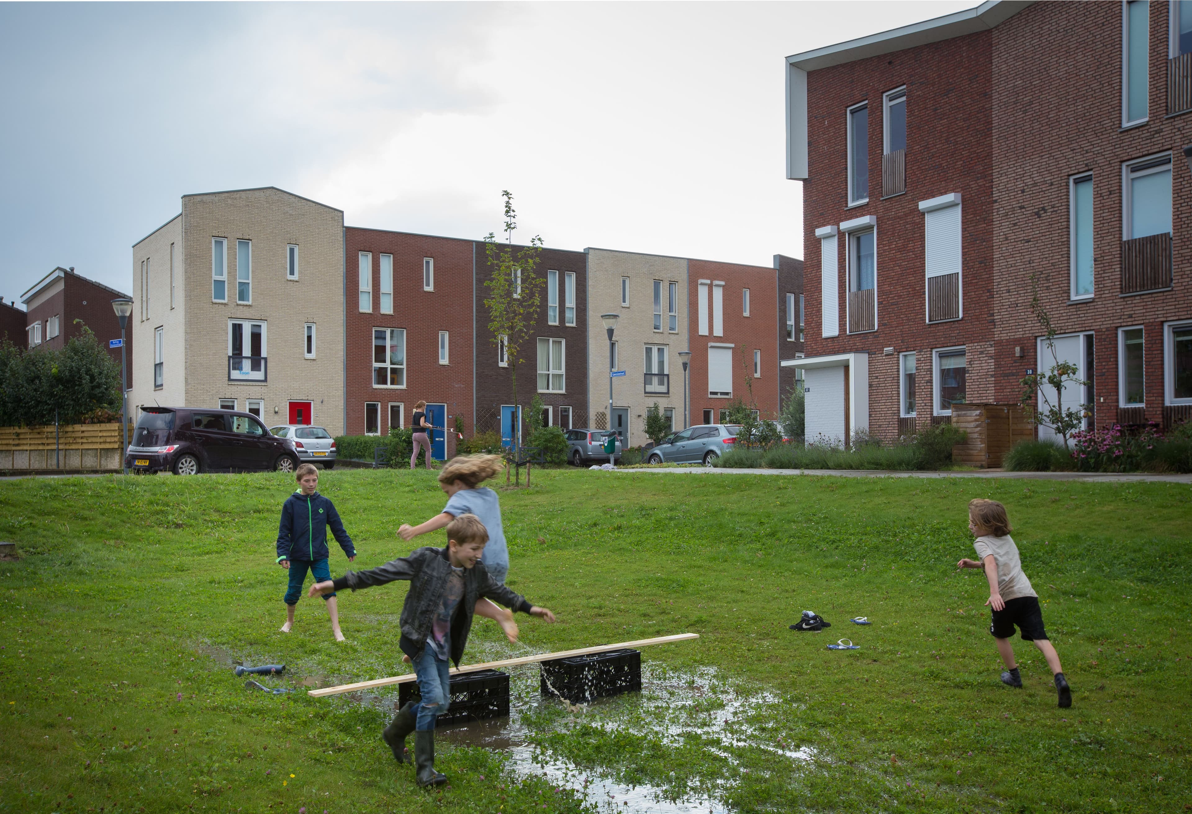 4 kinderen spelen rond 2 kratjes en een plank in een wadi