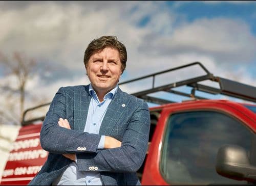 Mark Luikens leunend tegen een rood busje